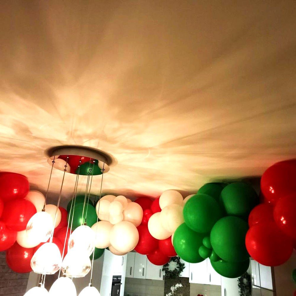 Red, green and cream organic balloon garland along a ceiling
